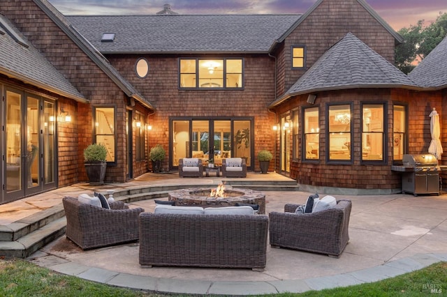 back house at dusk featuring a patio, french doors, and an outdoor living space with a fire pit