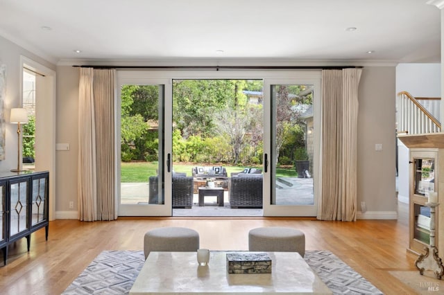 living room featuring light hardwood / wood-style flooring, ornamental molding, and a wealth of natural light