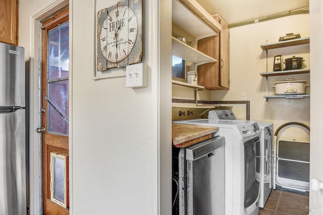 laundry room with laundry area, separate washer and dryer, and dark tile patterned flooring