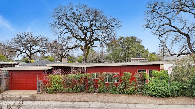 mid-century home with board and batten siding, driveway, a chimney, and an attached garage