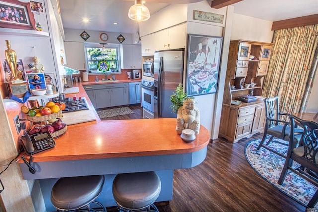 kitchen featuring white cabinets, kitchen peninsula, decorative light fixtures, stainless steel appliances, and dark hardwood / wood-style flooring