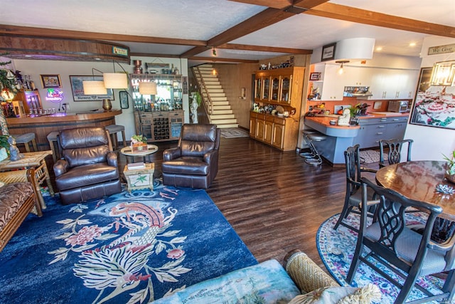 living room with bar area, beam ceiling, and dark hardwood / wood-style flooring