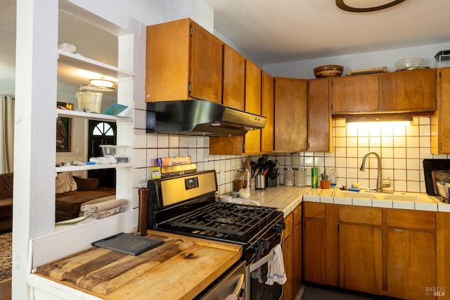 kitchen featuring tile countertops, gas range, sink, and tasteful backsplash