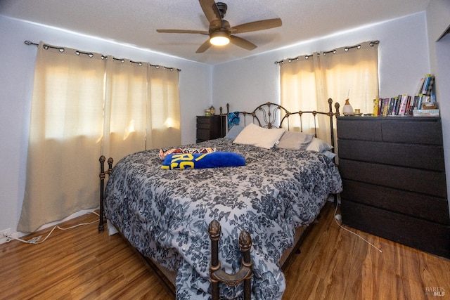 bedroom with multiple windows, ceiling fan, and hardwood / wood-style flooring