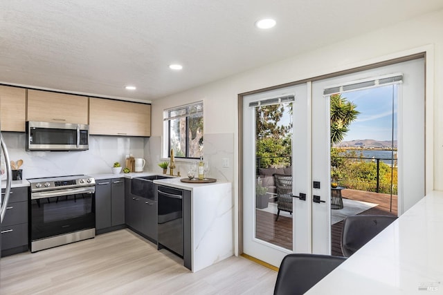 kitchen featuring french doors, stainless steel appliances, light hardwood / wood-style floors, and decorative backsplash