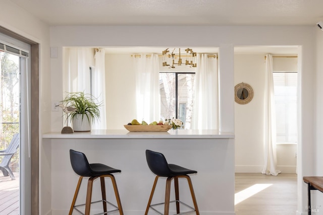 kitchen with a breakfast bar area, light hardwood / wood-style floors, and a wall unit AC