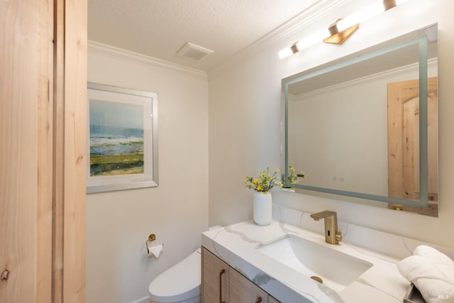 bathroom with a textured ceiling, ornamental molding, vanity, and toilet