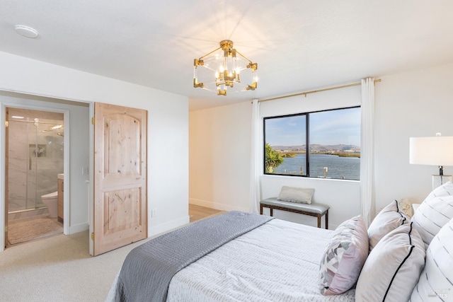 carpeted bedroom with a notable chandelier, a water view, and ensuite bathroom