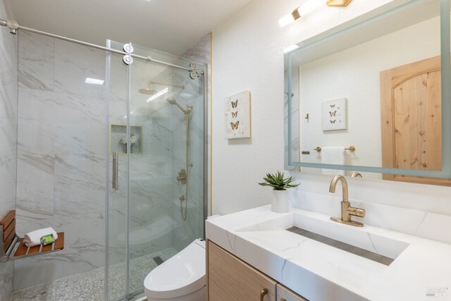 bathroom with walk in shower, vanity, and toilet