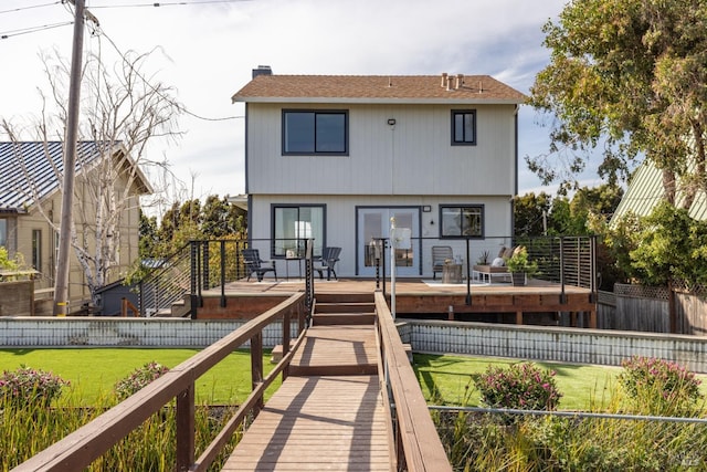 rear view of house with french doors, a deck, and a yard