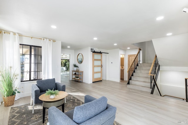 living room with a barn door and light wood-type flooring