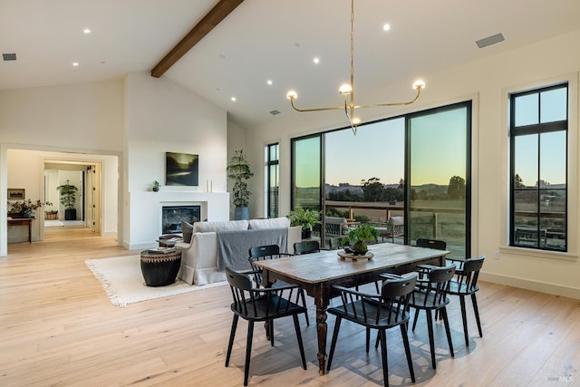 dining area with a notable chandelier, beam ceiling, light hardwood / wood-style floors, and high vaulted ceiling