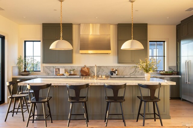 kitchen featuring a kitchen breakfast bar, light hardwood / wood-style floors, a kitchen island with sink, and sink