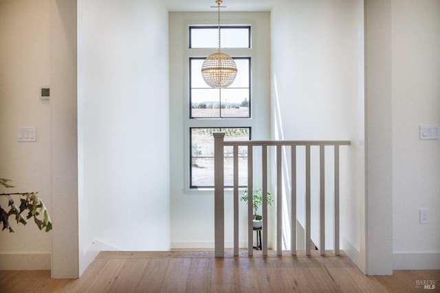 stairs with wood-type flooring and a chandelier