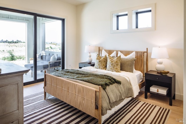 bedroom with access to outside, light wood-type flooring, and multiple windows