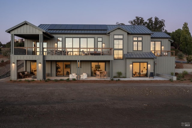 back house at dusk featuring a balcony