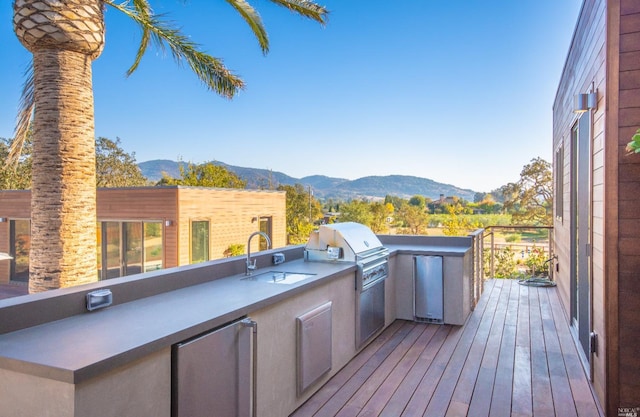 deck with a mountain view, sink, an outdoor kitchen, and area for grilling