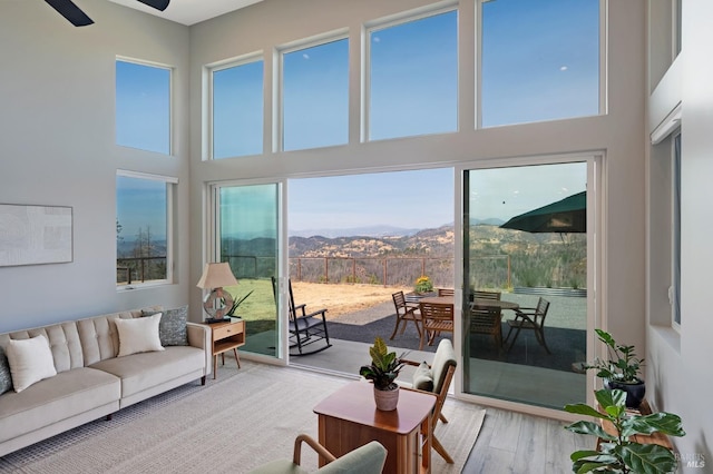 living area featuring a ceiling fan, a mountain view, a high ceiling, and wood finished floors