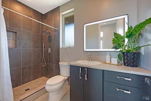 bathroom with vanity, a tile shower, toilet, and tile patterned floors