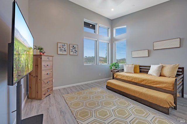 interior space featuring light wood-style floors, recessed lighting, a towering ceiling, and baseboards