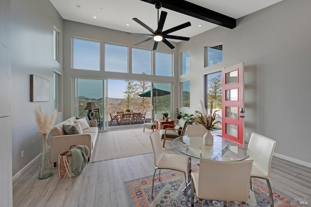 dining room with a high ceiling, wood finished floors, beam ceiling, and baseboards