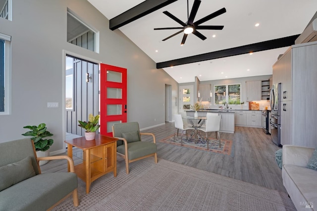 living room featuring a healthy amount of sunlight, light wood-style flooring, high vaulted ceiling, and beam ceiling