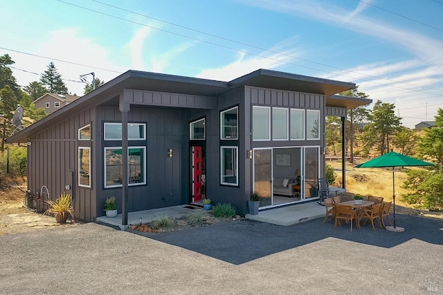 rear view of house featuring board and batten siding and a patio