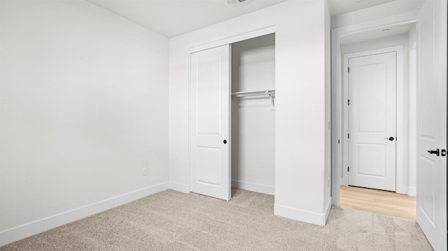 unfurnished bedroom with a closet and light carpet