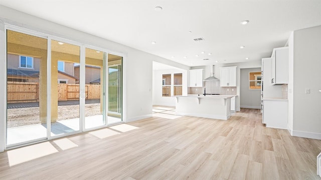 unfurnished living room with sink and light hardwood / wood-style flooring