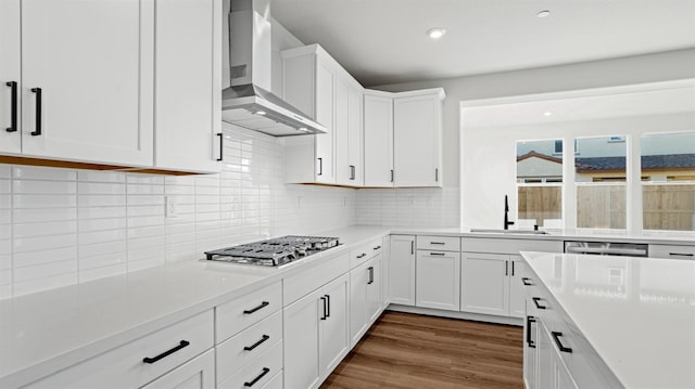 kitchen with appliances with stainless steel finishes, wall chimney exhaust hood, sink, and white cabinets