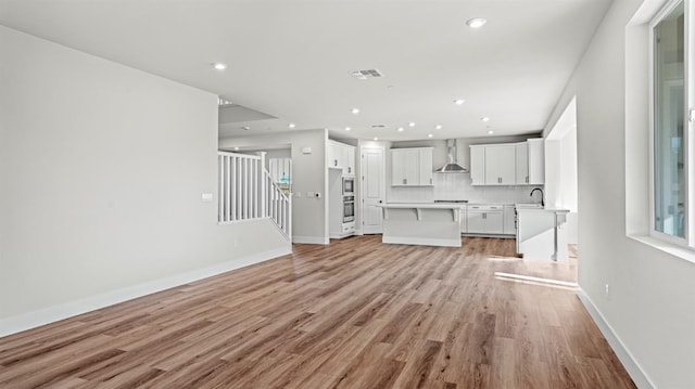 unfurnished living room with sink and light hardwood / wood-style floors