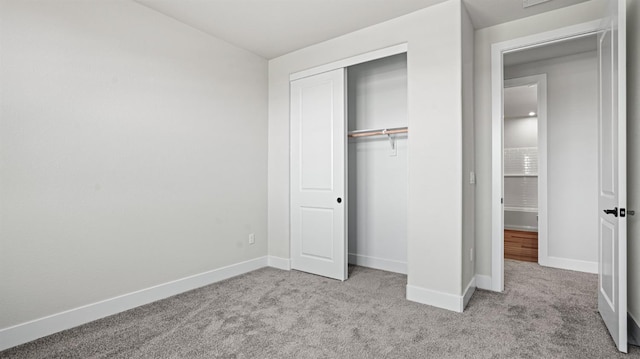 unfurnished bedroom with light colored carpet and a closet