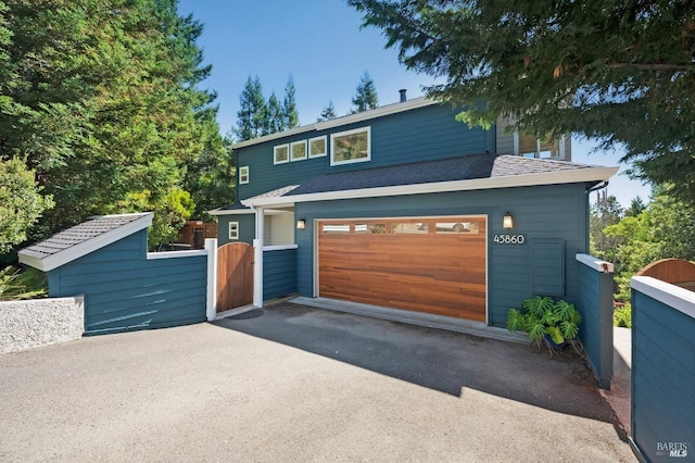 view of front of house featuring aphalt driveway, a gate, fence, and an attached garage