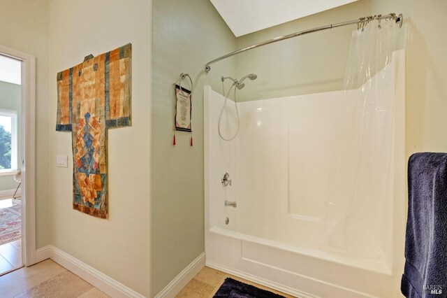 bathroom with shower / bath combo with shower curtain and tile patterned floors