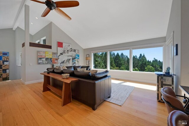 living room with high vaulted ceiling, beam ceiling, ceiling fan, and light hardwood / wood-style flooring