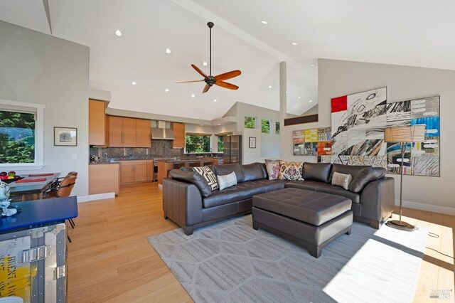 living room with high vaulted ceiling, beam ceiling, light hardwood / wood-style floors, and ceiling fan