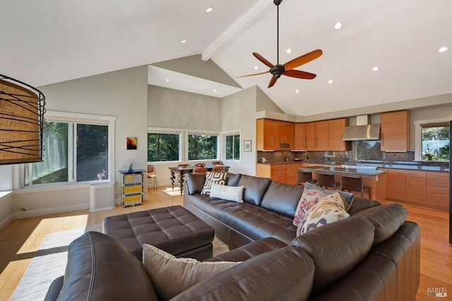 living room featuring high vaulted ceiling, light wood-type flooring, ceiling fan, and beamed ceiling