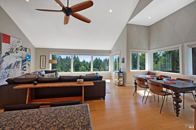 living room with high vaulted ceiling, ceiling fan, and light hardwood / wood-style flooring