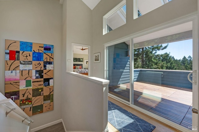 interior space with wood-type flooring, a high ceiling, and ceiling fan