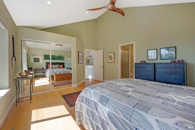 bedroom with a ceiling fan, wood finished floors, baseboards, high vaulted ceiling, and a closet