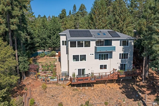 rear view of house featuring solar panels and a deck