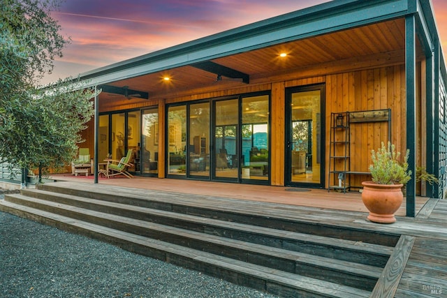 back house at dusk featuring a deck