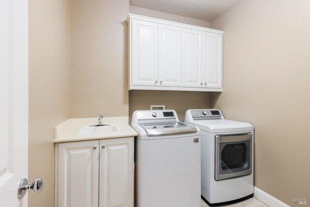 laundry room featuring sink, washing machine and clothes dryer, and cabinets