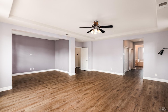 spare room featuring a tray ceiling, dark wood-type flooring, and ceiling fan