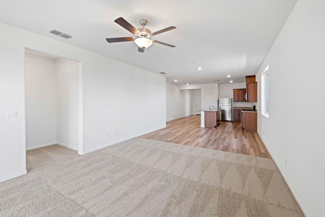 unfurnished living room featuring ceiling fan, recessed lighting, light carpet, visible vents, and baseboards