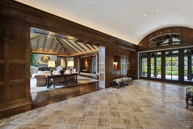 foyer entrance featuring beamed ceiling, wood walls, and high vaulted ceiling