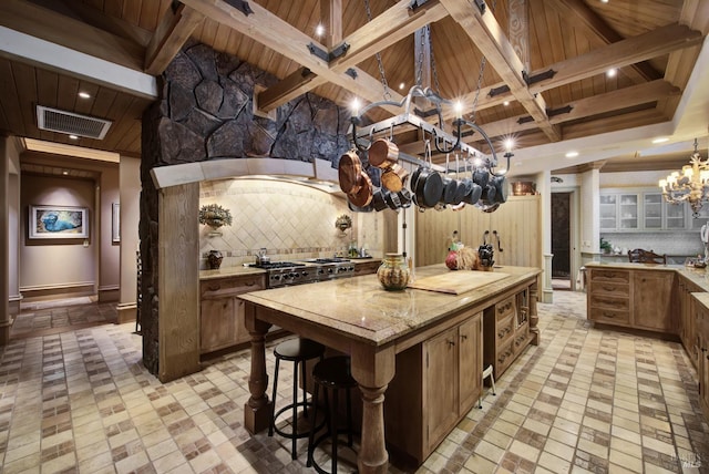 kitchen with a large island, a chandelier, beam ceiling, and tasteful backsplash