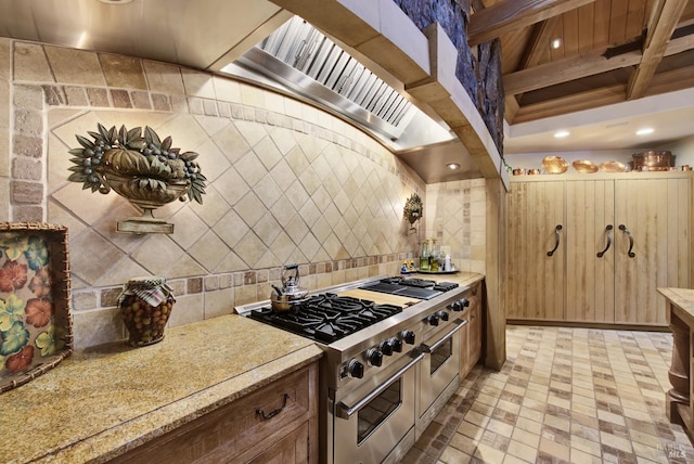 kitchen with light stone countertops, beam ceiling, and double oven range