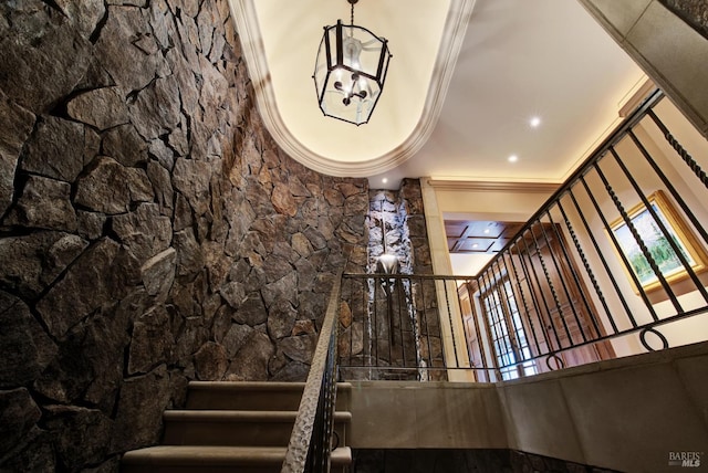 stairway featuring ornamental molding and an inviting chandelier