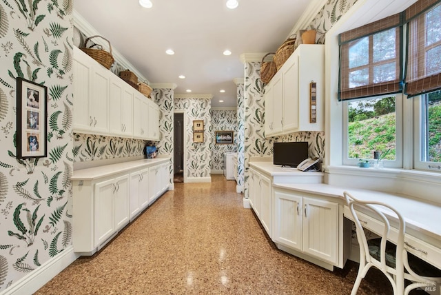 kitchen featuring white cabinets, crown molding, and built in desk